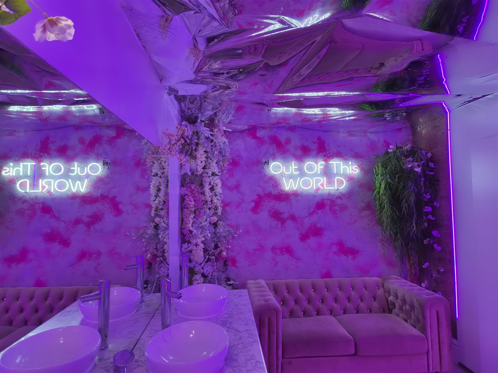 Mirrored vanity area with floral decoration and purple lighting.