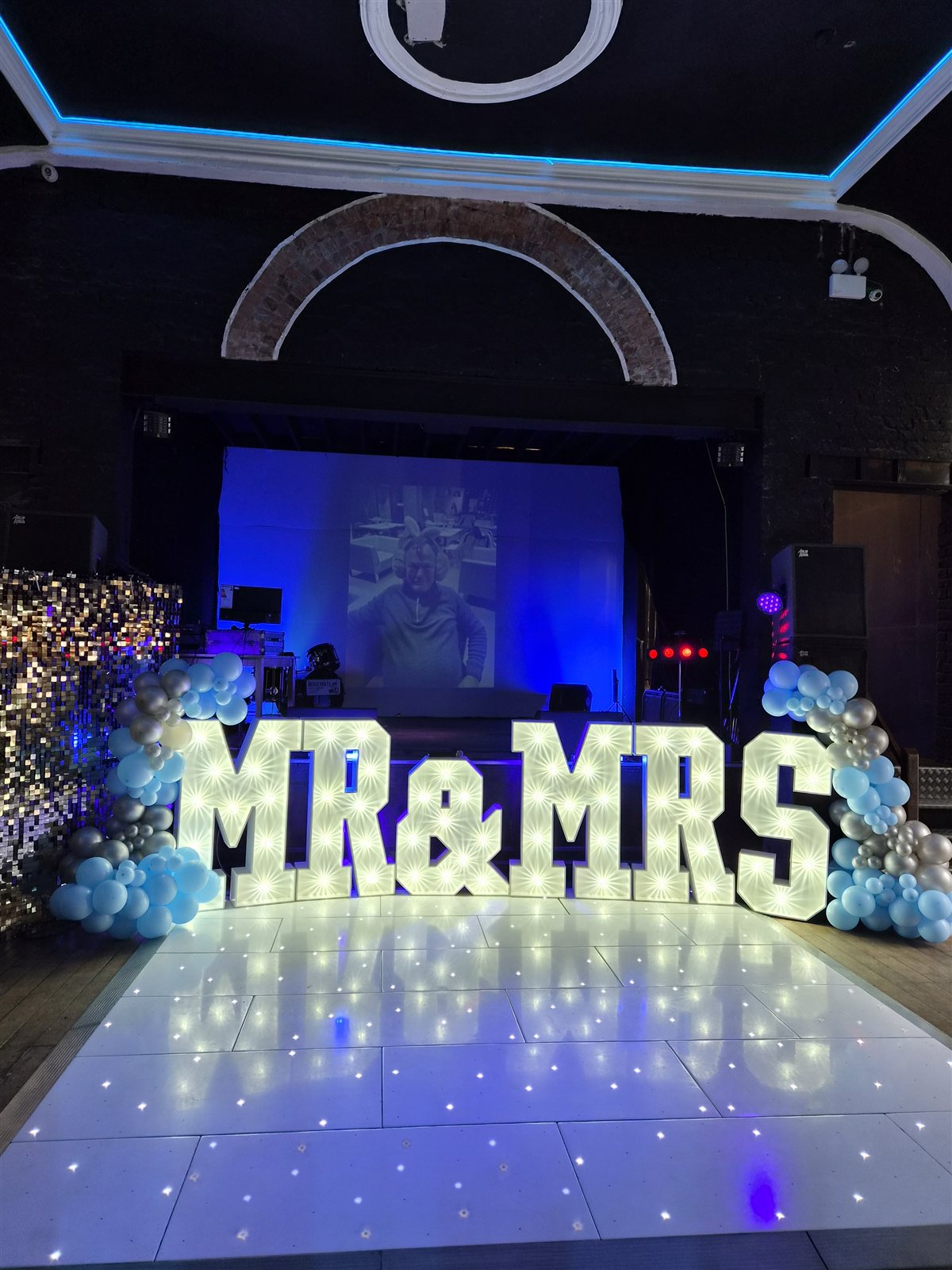 White dance floor and illuminated Mr & Mrs letters with blue and silver balloons.
