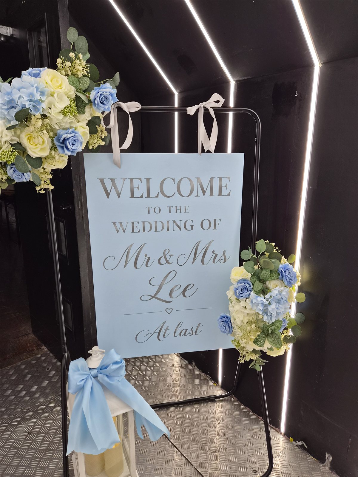 Wedding welcome sign decorated with blue and white flowers.